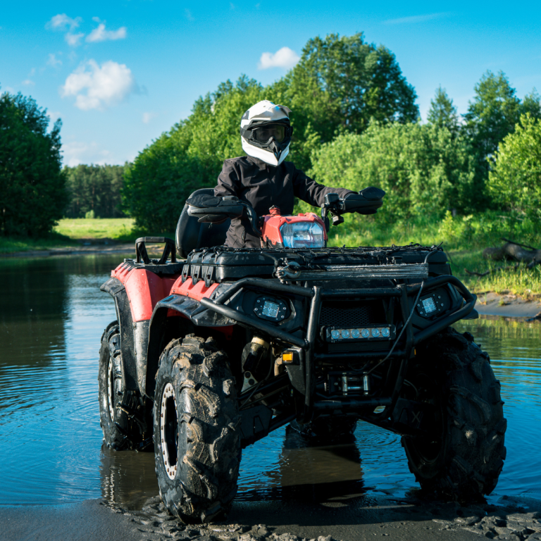 Person driving ATV through shallow water